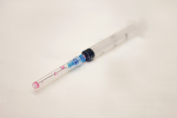 One syringe with cap and needle after using on the white bckground