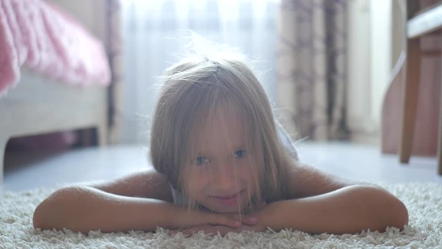 Pretty little girl lying on floor and smiling.