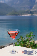 A glass of red martini on the seascape background.