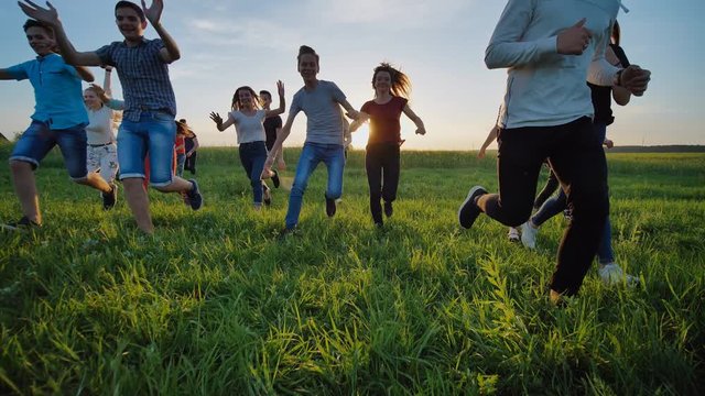 Group of friends running happily together in the grass