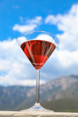A glass of red martini on the sky background.