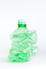 Crushed green plastic bottle on white background