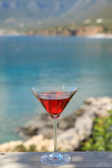A glass of red martini on the seascape background.