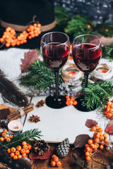 Mulled wine in glasses ,red berries,bumps and autumn branches on wooden table. Autumn or Winter concept.