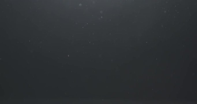 Slow motion real dust floating in air over dark background