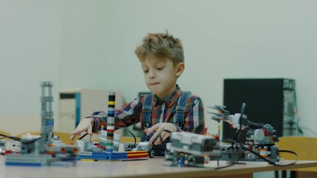 Young talented boy is in the engineering club working with robots. blocks robots on the table. Modern technologies. Boy playing indoor.