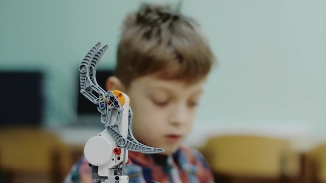 Close up shot of a lovely smart boy working on a new blocks robotic claw in a club. Learning how to work with control panel. Programming robots.