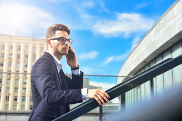 Business man stand at street holding a smartphone in office park