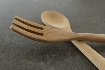 Wooden large spoon and fork on grey background - cooking eating concept