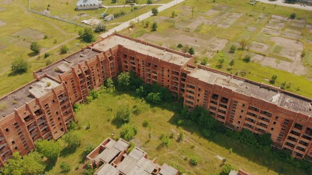 Flying above old abandoned construction. AERIAL: Flight over unfinished high-rise building with apartments. Drone view. Summer season. Abandoned city after disaster. HD footage.