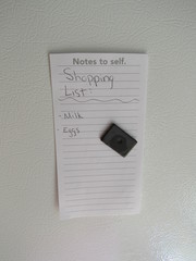 A shopping list with milk and eggs on a refrigerator 
