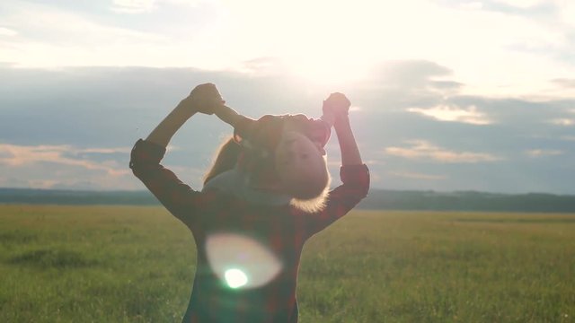 A little boy sits on the shoulders of mom In a Beautiful Summer Day At Sunset. Silhouette of a happy mother holding his child's shoulders against the sunset. The concept of happiness and family.