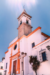 Fototapeta na wymiar Sun glare beams against a blue sky summer day above the 16th century church Parroquia de Las Angustias in Ayamonte, Huelva province, Andalusia, Spain.