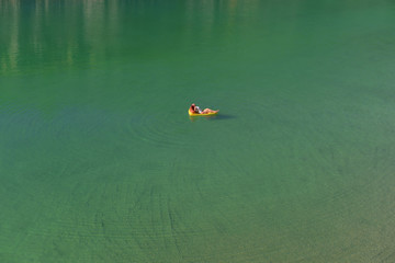 A young woman spends leisure time on an inflatable  sun bed in the middle of a green lake. She...