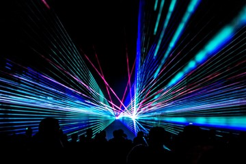Colorful laser show nightlife club stage with party people crowd. Luxury entertainment with audience silhouettes in nightclub event, festival or New Year's Eve. Beams and rays shining colorful lights - obrazy, fototapety, plakaty