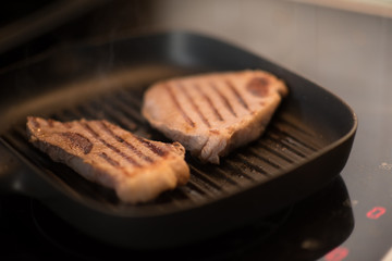 Grilled Black Angus Steak Striploin on frying cast iron Grill pan on dark background.