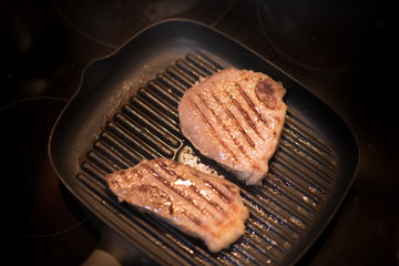 Grilled Black Angus Steak Striploin on frying cast iron Grill pan on dark background.