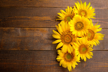 Many beautiful bright yellow sunflowers on a brown wooden background. top view with a place for...