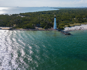 The restored Cape Florida Lighthouse on Biscayne Bay south of Miami Florida and the clear gorgeous waters and reefs as seen from above via drone