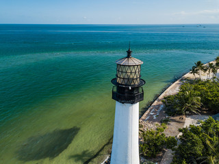Fototapeta na wymiar The restored Cape Florida Lighthouse on Biscayne Bay south of Miami Florida and the clear gorgeous waters and reefs as seen from above via drone