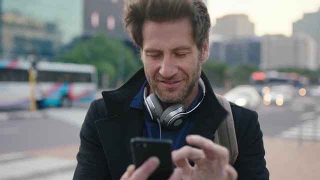 slow motion portrait of attractive caucasian man in busy city street texting browsing using smartphone mobile app urban commuting 