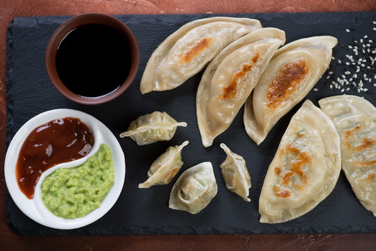 Above view of fried korean wontons and potstickers with dipping sauces, close-up