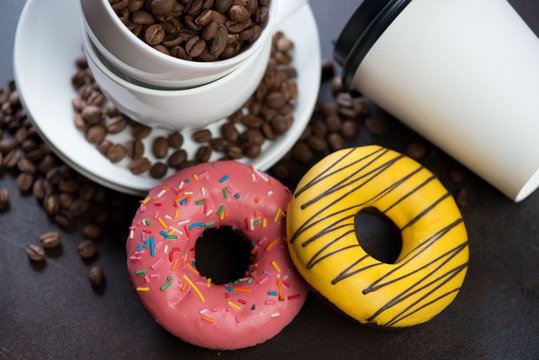Couple of donuts with coffee cups and coffee beans in the background, selective focus, close-up
