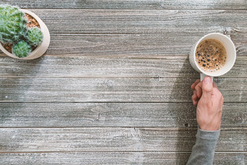Person holding a coffee mug on a wooden desk overhead view
