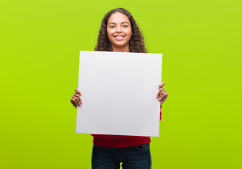 Young hispanic woman holding blank banner with a happy face standing and smiling with a confident...