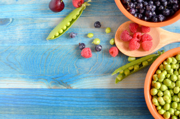 peas and berries on a blue wooden background