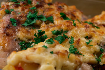 Rosy crust of cheese on baked chicken in the oven, sprinkled with chopped parsley.