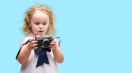 Beautiful blonde toddler taking pictures with vintage camera