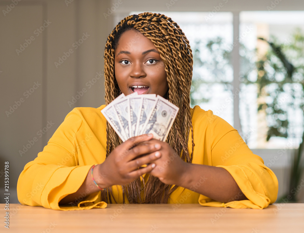 Canvas Prints African american woman holding dollars scared in shock with a surprise face, afraid and excited with fear expression