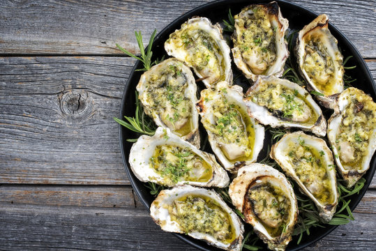 Barbecue überbackene frische offene Austern mit Knoblauch und  Kräuter angeboten als Draufsicht auf einem Teller mit Textfreiraum links  