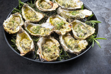 Barbecue overbaked fresh opened oyster with garlic and herbs offered as top view on a tray