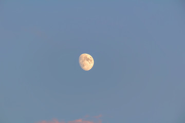 Detail of Moon on blue sky with sunset clouds