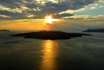 Sunset with Volcano Thira Santorini Greece with Silhouette and lens flare.