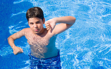 Young child on holidays at the swimming pool by the beach with angry face, negative sign showing dislike with thumbs down, rejection concept