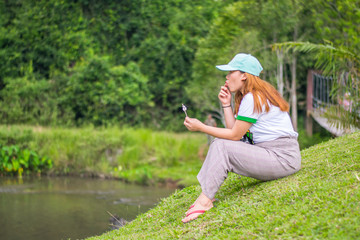 Fototapeta premium Asian female woman sitting on the ground eating ice cream