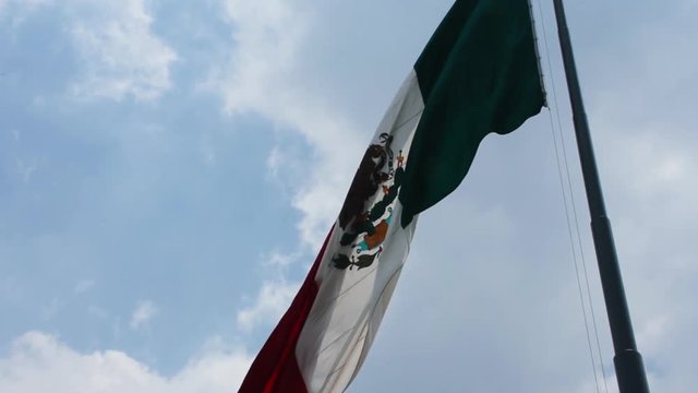Mexican flag waving in the wind high over Zocalo, Mexico City main square