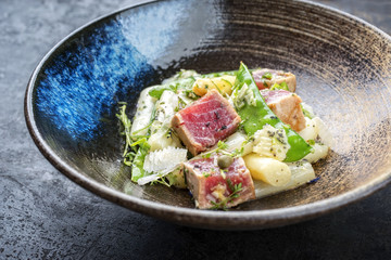 Modern fried tuna fish tataki filet salad with white asparagus sugar snaps and parmesan cheese as top view on a plate
