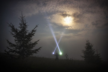 Man shines a flashlight in the night moon sky