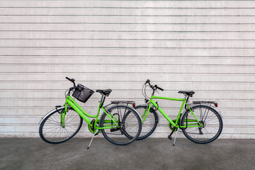 Green colored bicycles against stripes patterned concrete wall