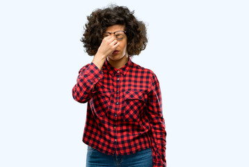 Beautiful arab woman with sleepy expression, being overworked and tired, rubbes nose because of weariness