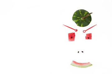 Funny Face person made of a hat from watermelon, cubes of watermelon and sunflower seeds. Top view. White background, horizontal shot. The place for an inscription