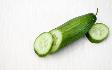 Isolated cucumbers. One whole cucumber and slices of cucumber isolated on white background