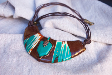Handmade autumn necklace from polymer clay in  brown and green colors with emerald stone. Boho ethnic jewelry. Fashion unique background.