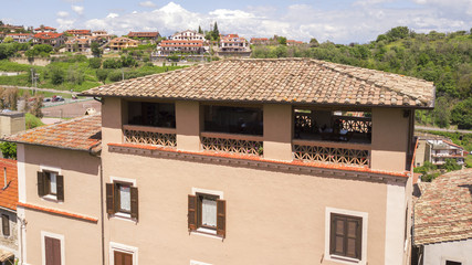 Aerial detail of a small terrace between the roof tiles of a small Italian village. On this balcony there are a couple of chairs and a table for nice summer days.