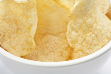 Delicious golden potato chips in a white bowl isolated on white background close-up.