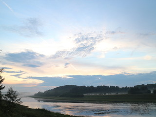 Naklejka na ściany i meble evening clouds on the river after sunset
